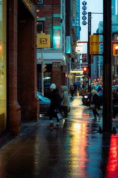Pedestrians navigate a wet downtown Toronto street after rain during winter.