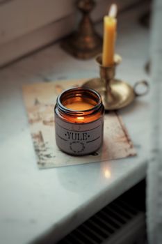 Warm yule candle creating a cozy ambience on a marble surface by a window.
