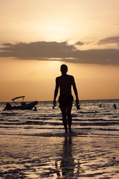 A serene beach scene with a person walking towards a stunning sunset, capturing tranquility and relaxation.