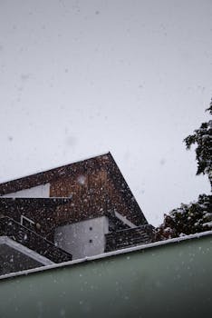 Modern building in a snowy winter scene, showcasing architecture amid snowfall.