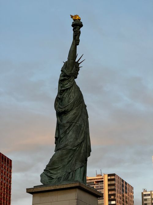 Free Side view of the Statue of Liberty replica against a blue sky in Paris, France. Stock Photo