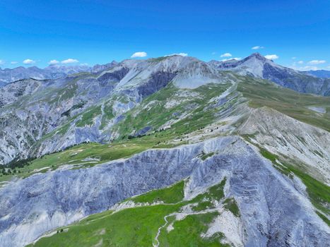 Dramatic aerial view of the Alpine mountains in Mercantour National Park, showing vibrant greenery and rugged peaks.