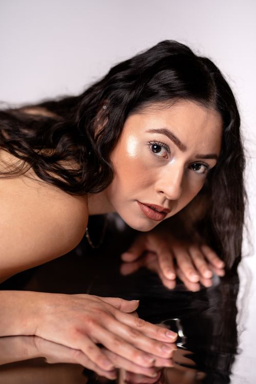 Free Captivating portrait of a woman gazing into her reflection on a dark surface. Stock Photo