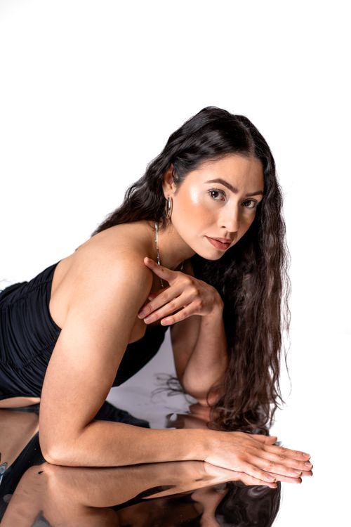 Free A stylish woman posed on a reflective surface, showcasing elegance and poise. Stock Photo