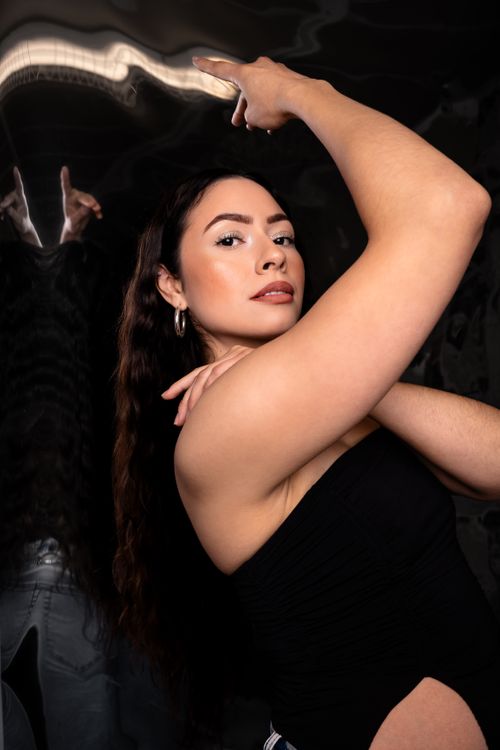 Free Confident woman with raised arm, stylish and contemporary portrait reflecting strength and elegance. Stock Photo