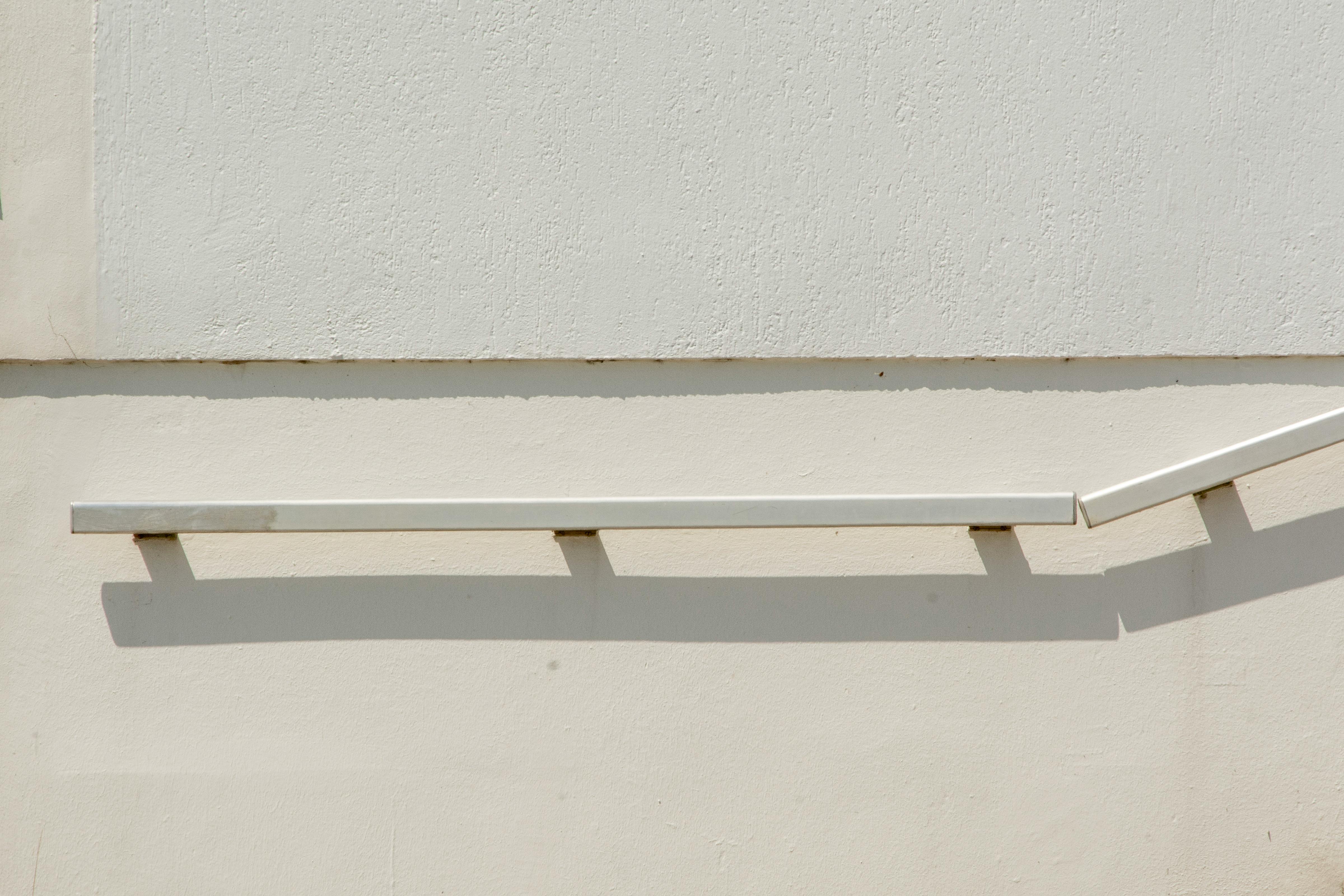 Gratuit Balustradă simplă albă care aruncă o umbră pe un perete simplu, prezentând un design minimalist. Fotografie de stoc