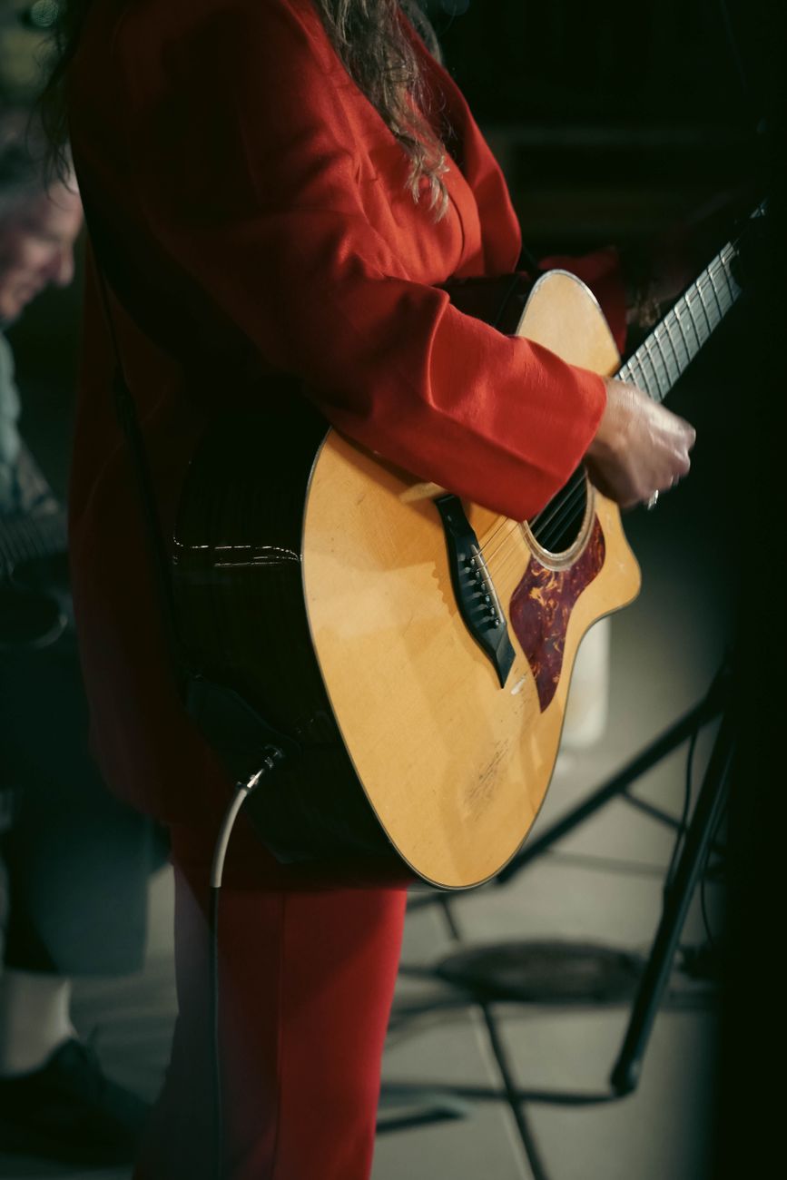 Muzikant die tijdens een liveoptreden een akoestische gitaar bespeelt en zo een levendige sfeer creëert.