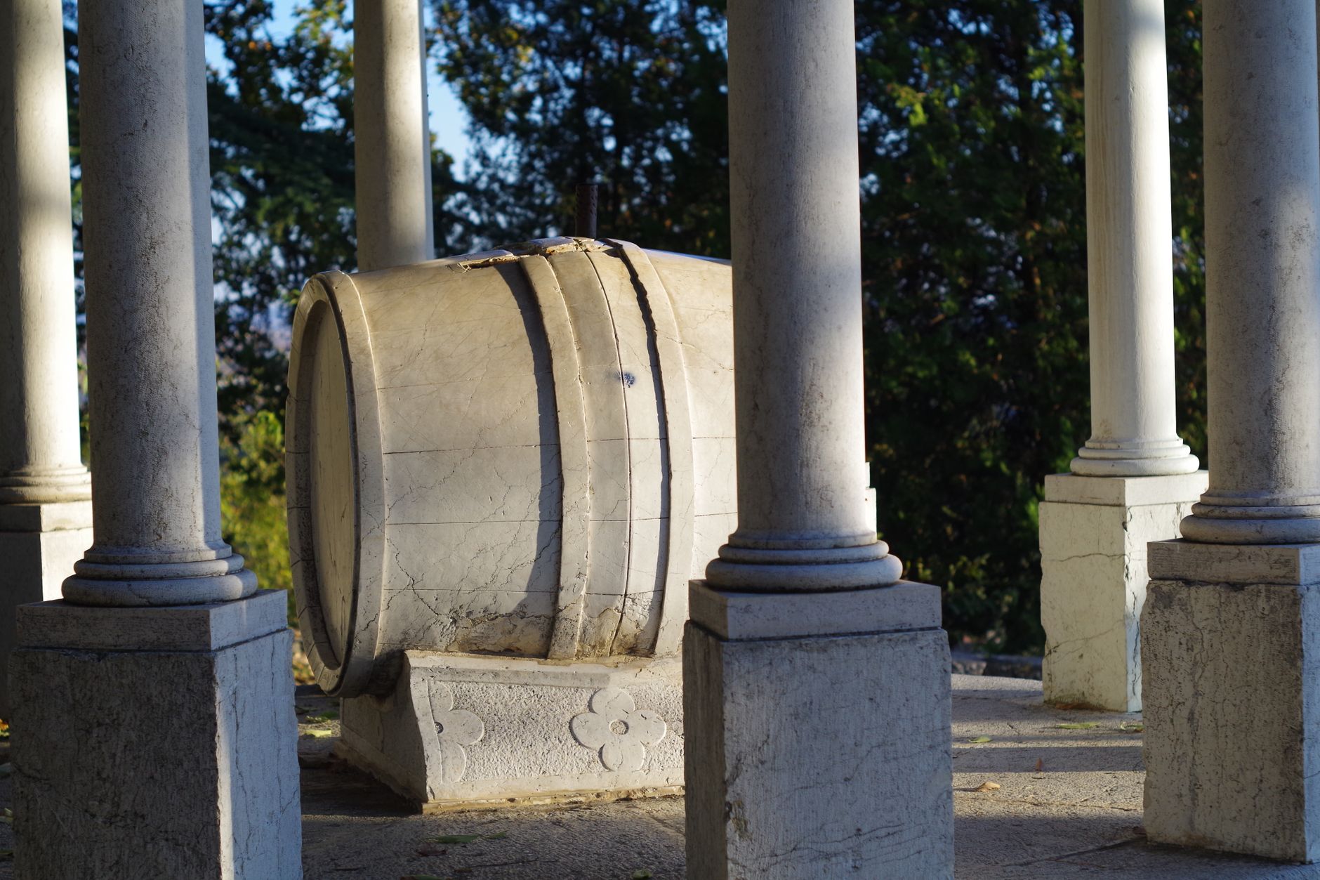Photograph of a marble cask surrounded by stone columns in an outdoor setting.