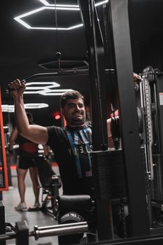 Male performing strength training on a machine in a modern gym.