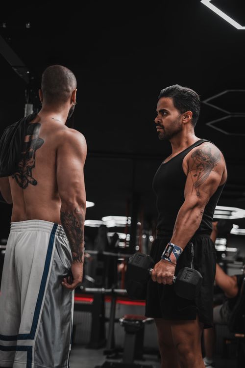 Free Two men focused on strength training, lifting weights in a modern gym setting. Stock Photo