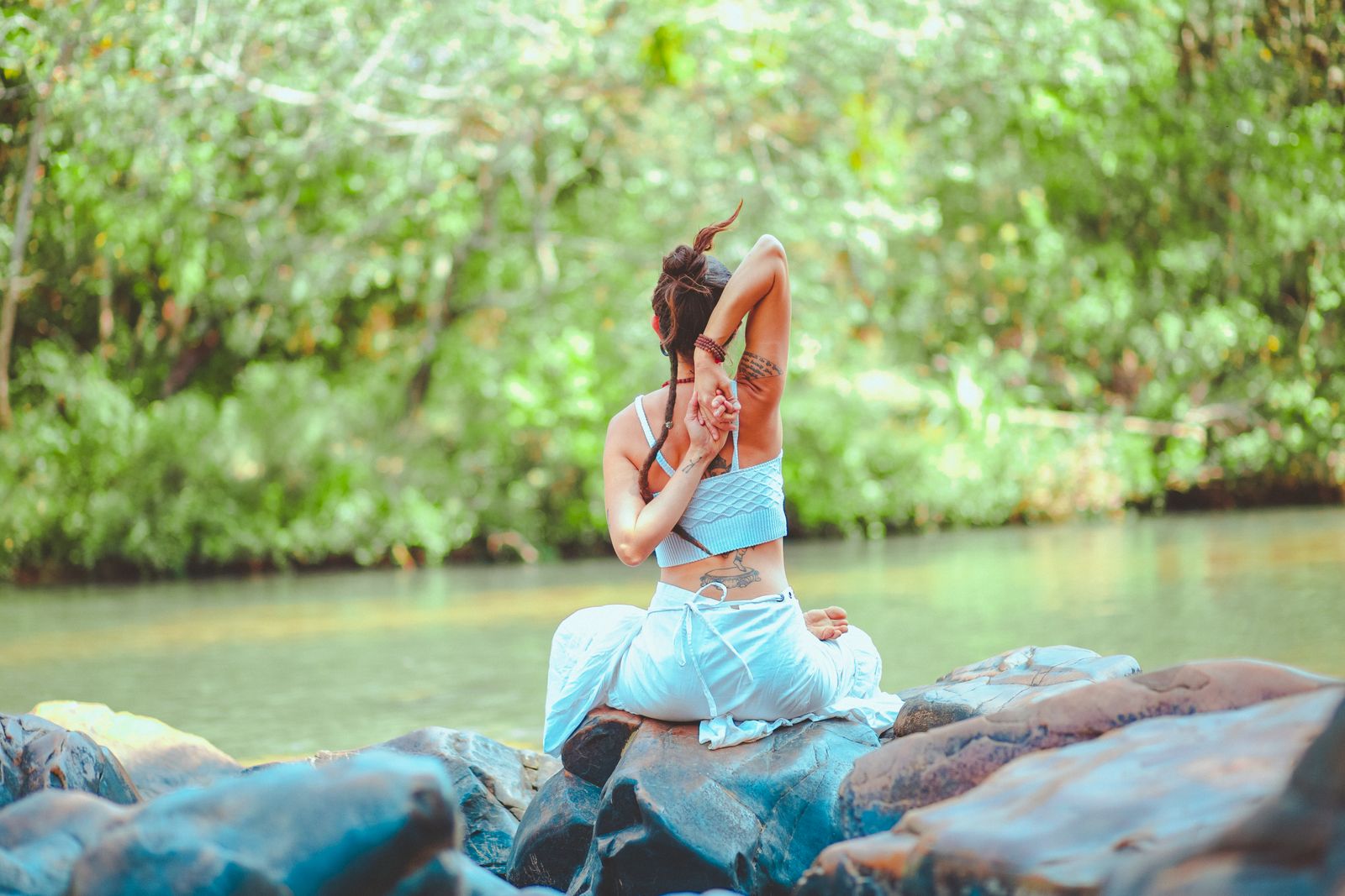 Woman sitting in quiet meditation outdoors near rocks, grounding practice for chakra balance