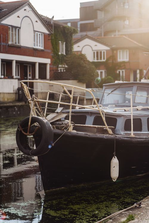 Free Serene canal scene in London featuring a moored boat and picturesque houses on a sunny day. Stock Photo