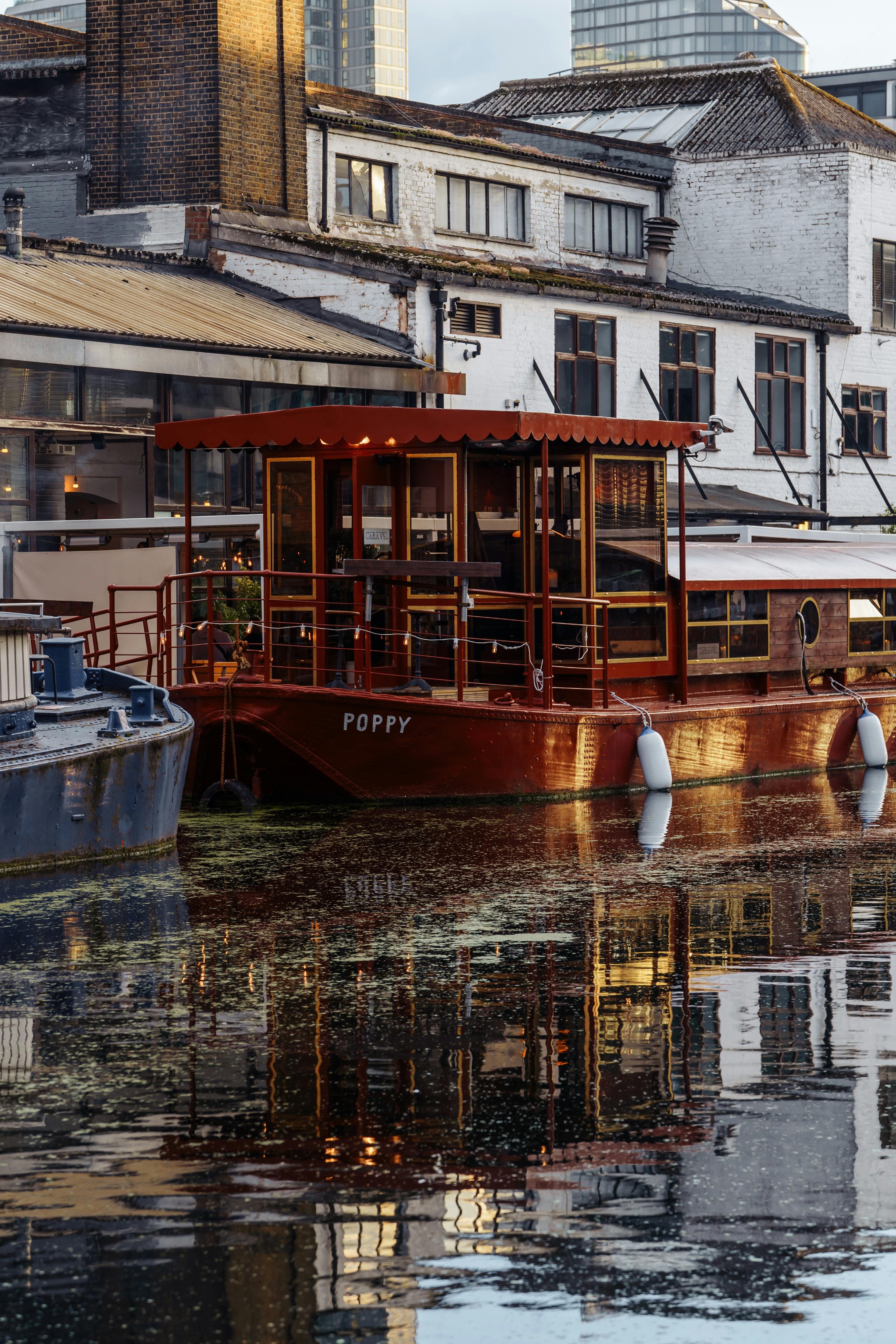 A tranquil canal scene featuring a moored boat reflecting modern architecture in London.