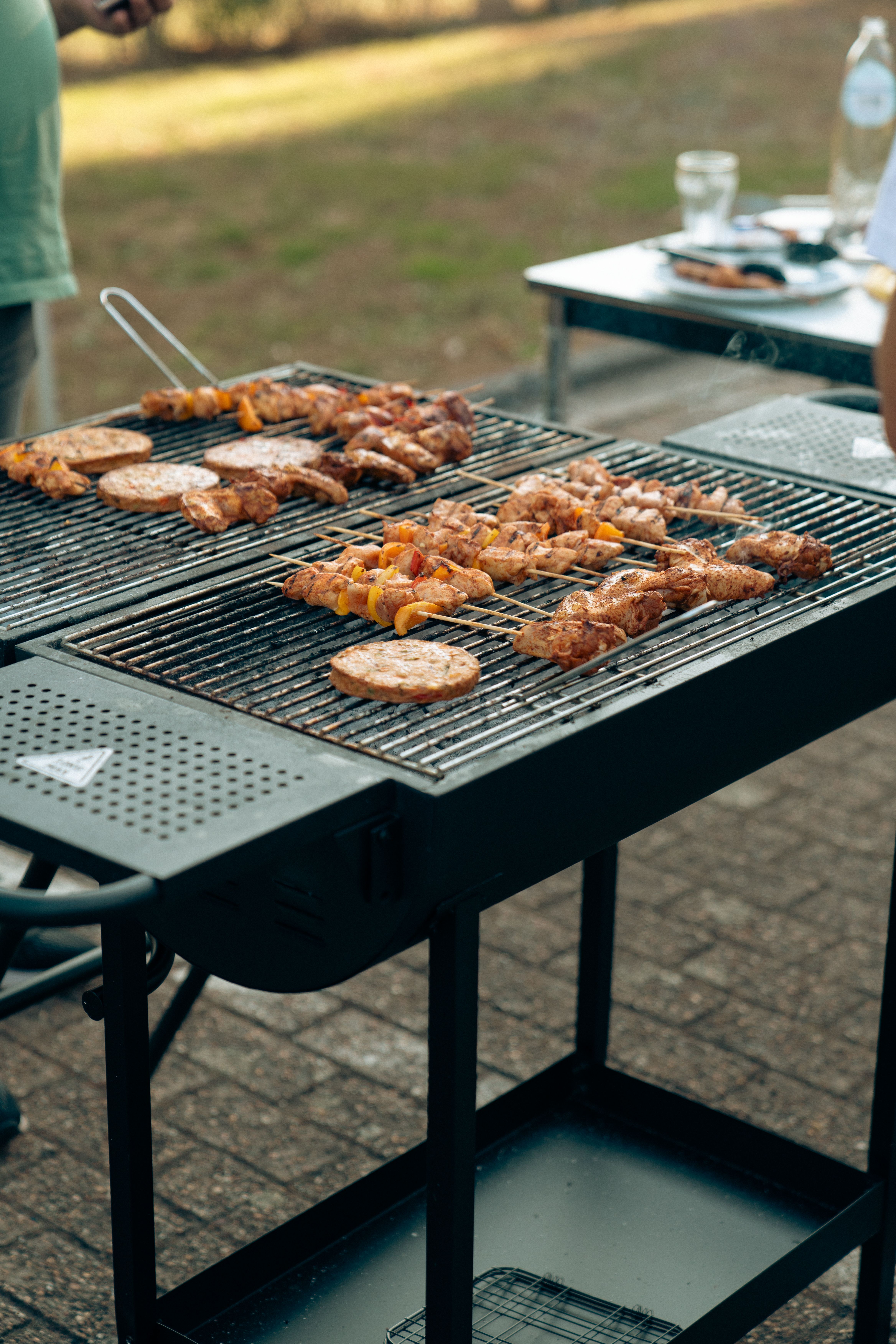 Delicious assortment of meats grilling outdoors on a charcoal barbecue.