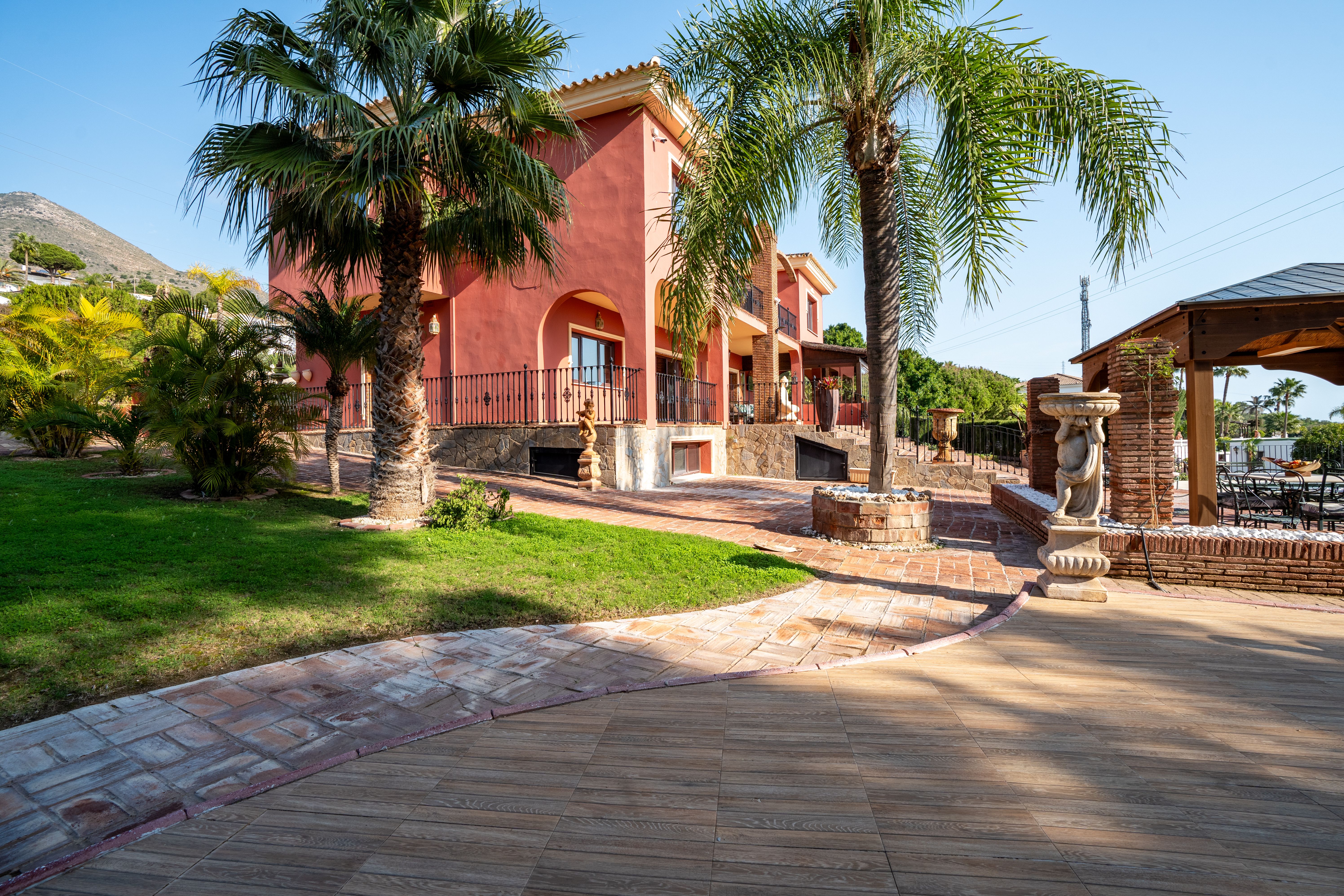 Elegant Mediterranean villa with palm trees and garden in a sunny outdoor setting.