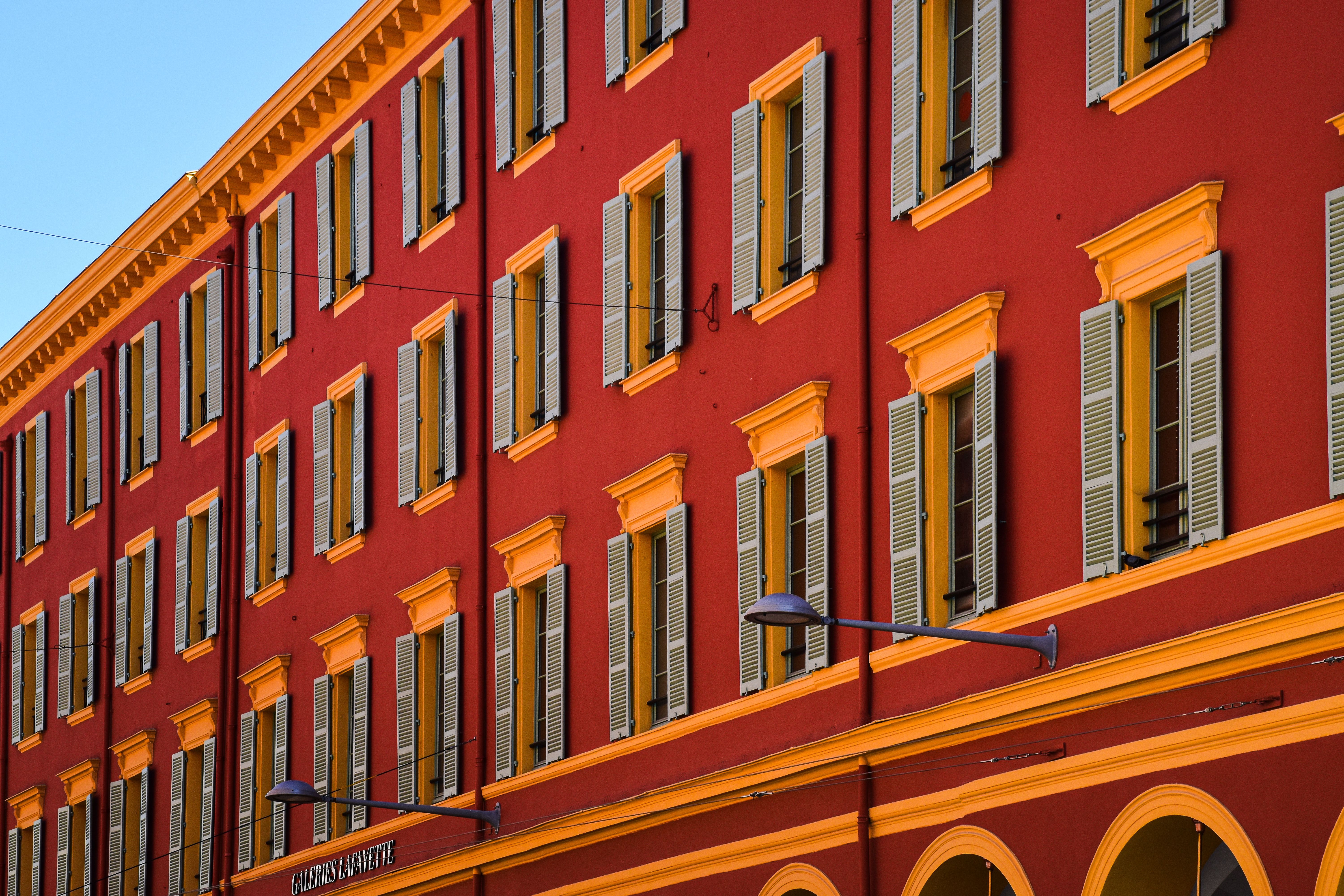 Vibrant facade of historic building in Nice, France with striking red and yellow colors.