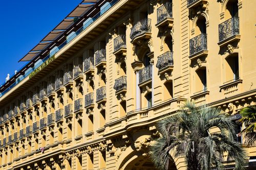 Free Beautiful historic building facade in Provence-Alpes-Côte d'Azur, France with intricate balconies and palm trees. Stock Photo