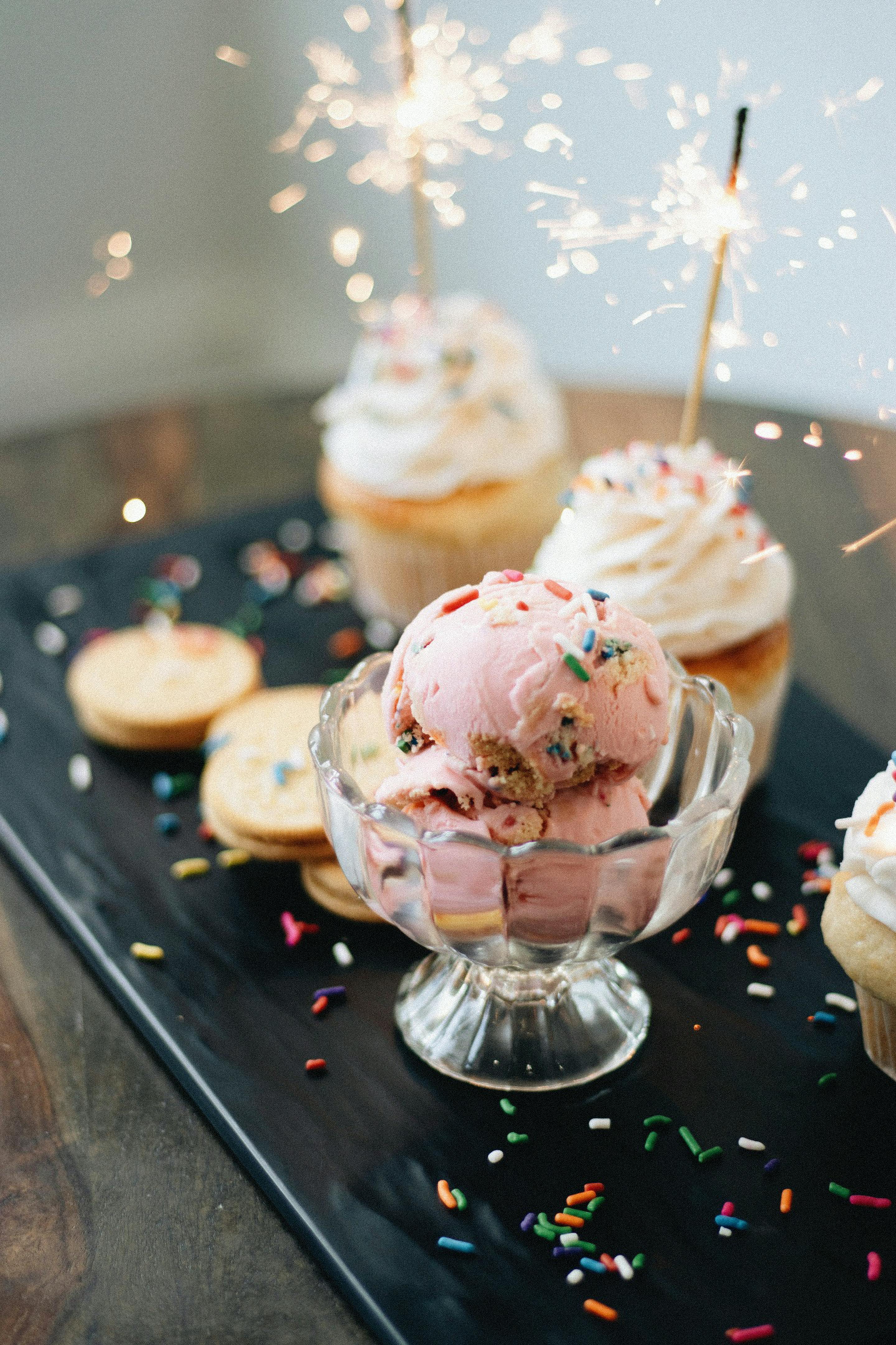 Stylish artisan dessert display featuring strawberry ice cream and sparkling cupcakes.
