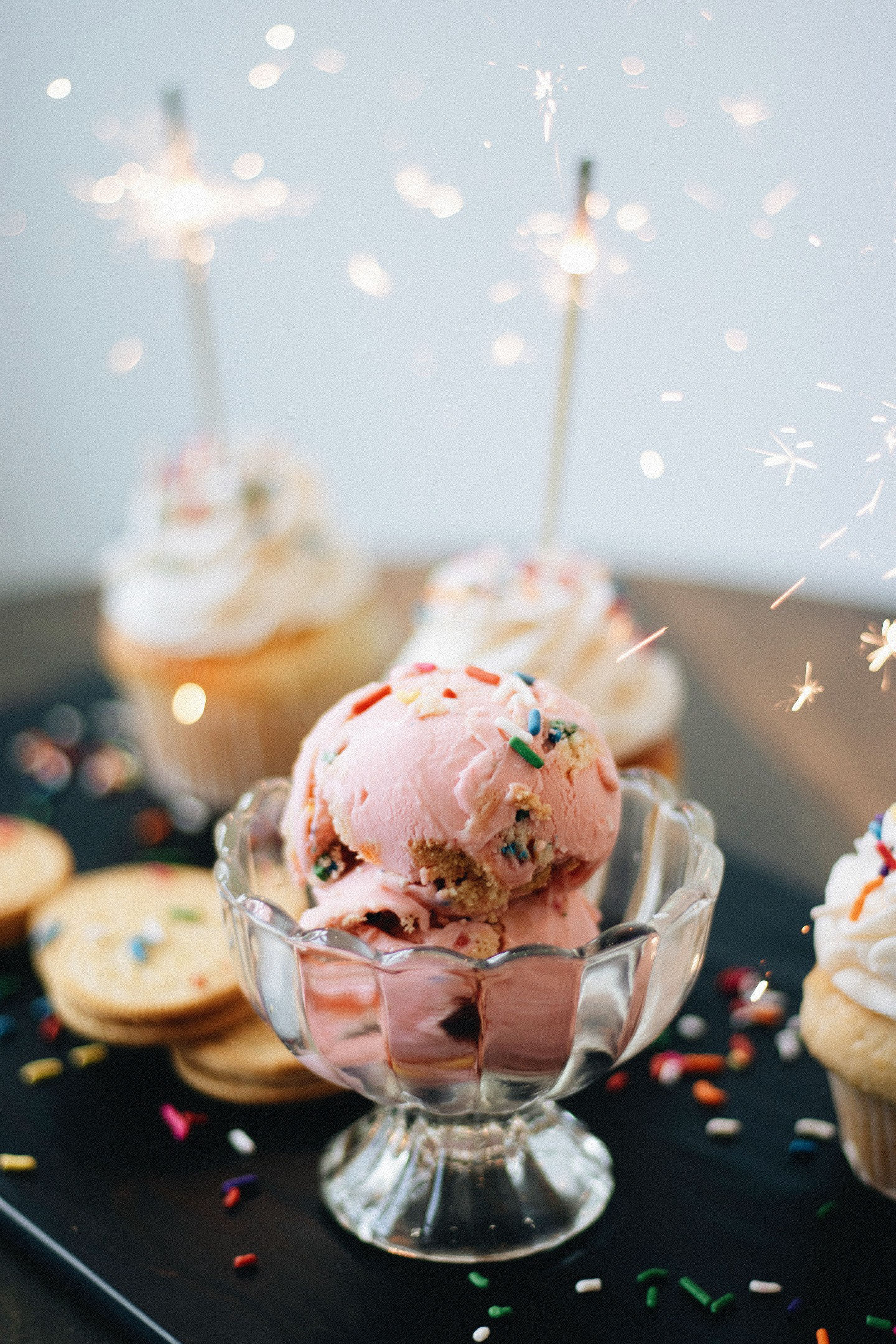 Delicious pink ice cream and cupcakes adorned with sparklers and sprinkles.