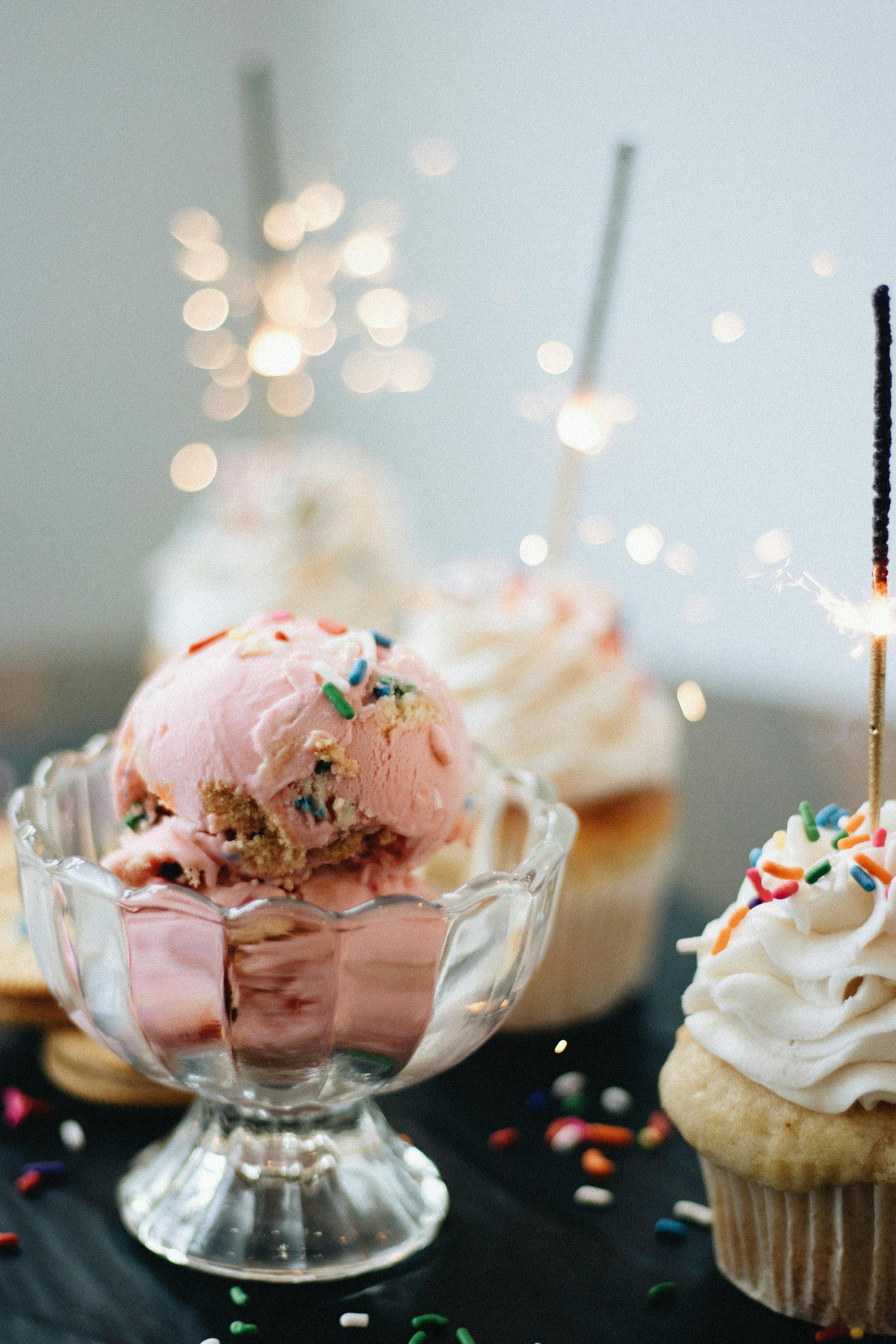 Delightful pink ice cream with cupcakes and sparklers for a festive treat.
