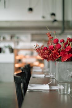 Stylish indoor dining setting with vibrant red flowers accentuating a modern table arrangement.