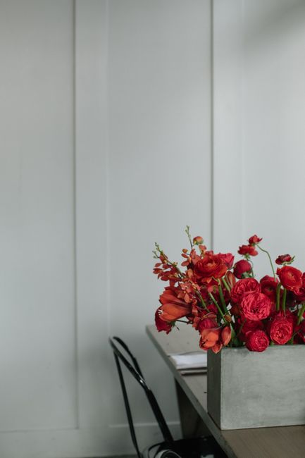 A minimalist indoor scene featuring a bouquet of vibrant red flowers on a table.