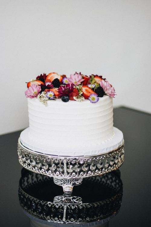 Free White layered cake elegantly decorated with fresh fruits and flowers. Stock Photo