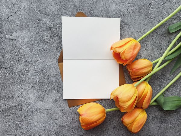A blank folded card with orange tulips on a stone surface — photo by Jennie Ra on Pexels