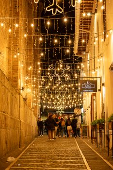 Charming street in Cuenca adorned with festive lights and decorations at night.