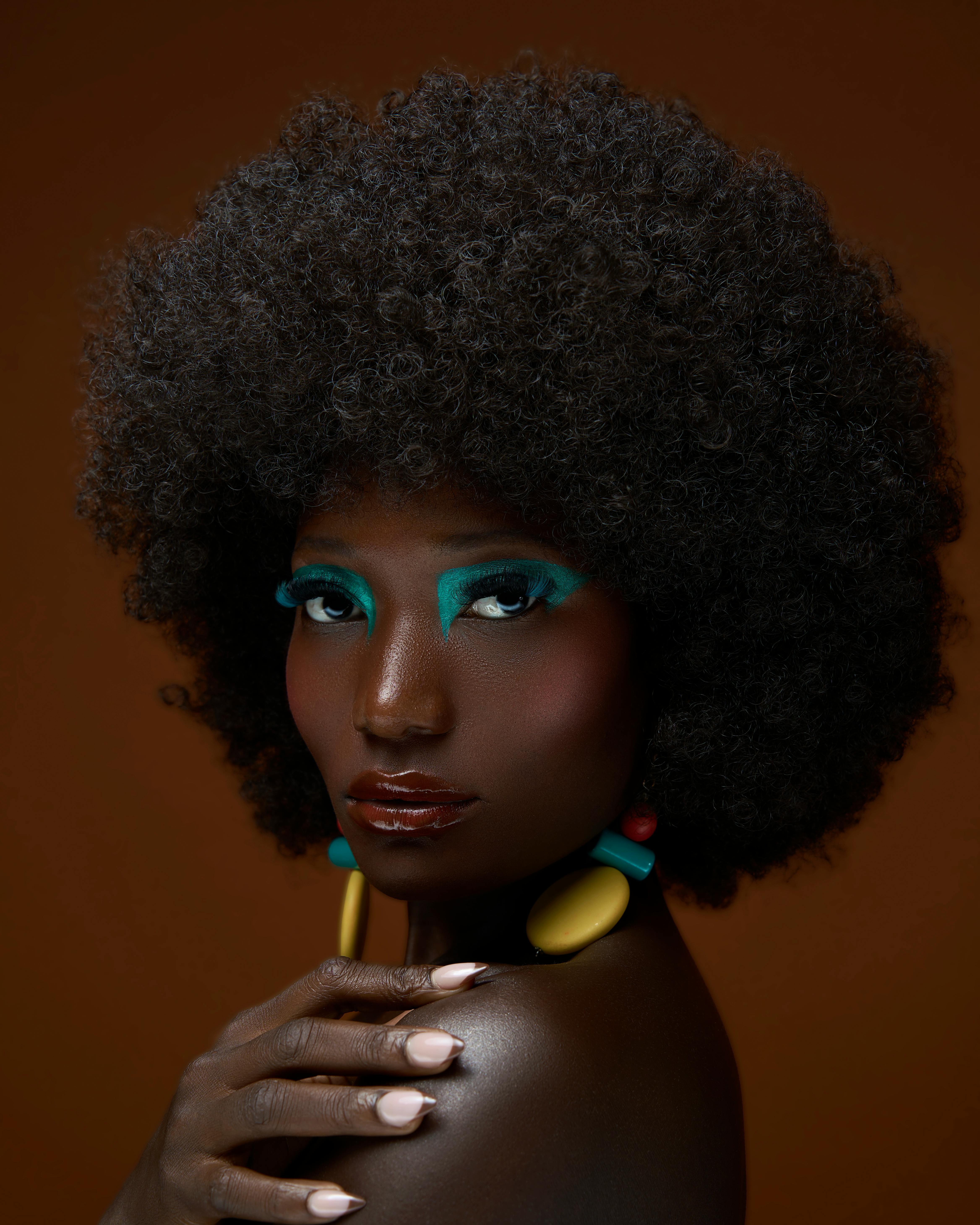 Dramatic portrait showcasing vibrant makeup and style against a warm backdrop.