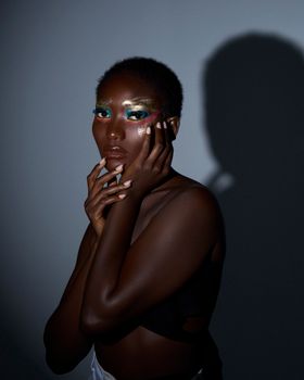 Captivating artistic portrait of a woman with vivid makeup against a dramatic shadow.