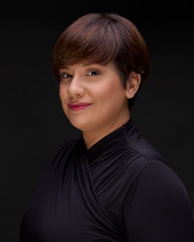 Elegant studio portrait of a woman with short hair against a black background.