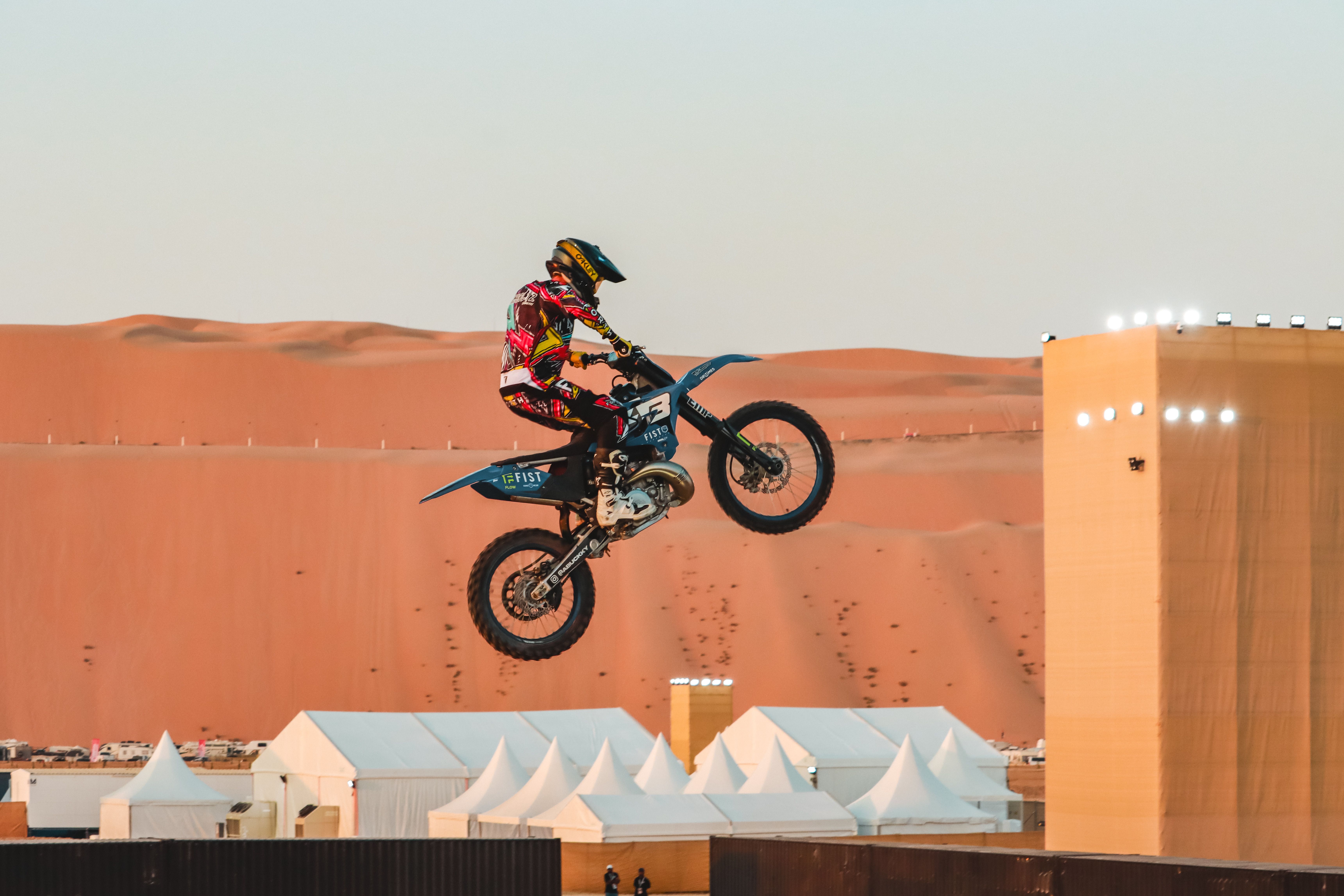 A motorbike stunt performer leaps high in Abu Dhabi's stunning desert landscape.