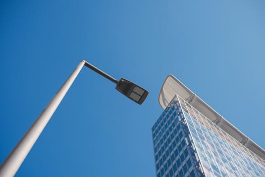 A contemporary skyscraper and streetlamp set against a clear blue sky, capturing urban architectural design.