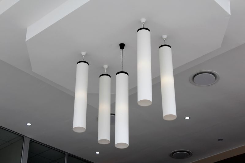 Cylindrical pendant lights on a white ceiling, photo by Fortune Dlamini on Pexels