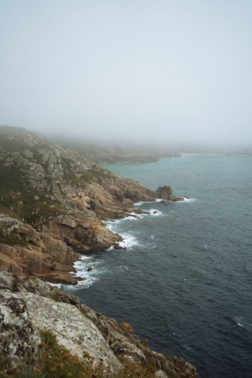 Free Foggy view of England's rocky coastline with rugged cliffs and ocean waves. Stock Photo