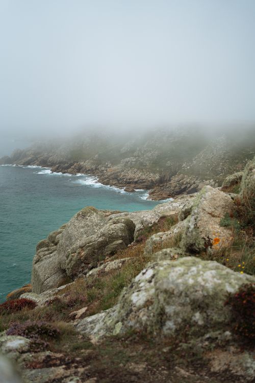 Free Fog hangs over England's rocky coastline, showcasing nature's rugged beauty. Stock Photo