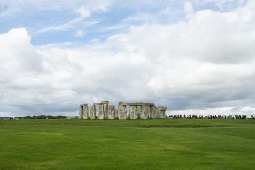 Free Iconic Stonehenge with tourists on a cloudy day in England, showcasing Neolithic architecture. Stock Photo