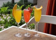 Three vibrant fruit mimosas with garnishes, perfect for a sunny day brunch.