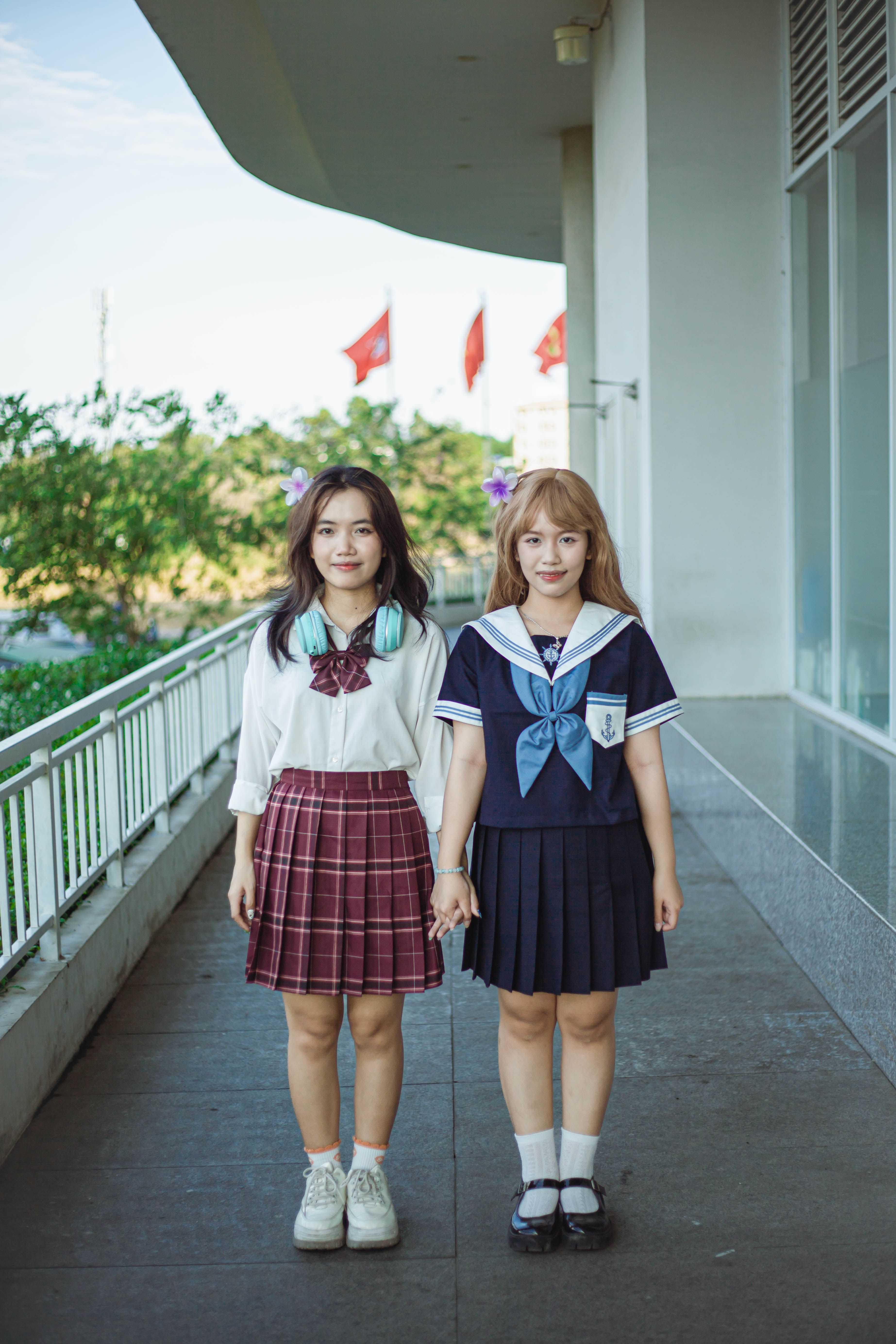 Two Girls in School Uniforms Holding Hands Outdoors · Free Stock Photo