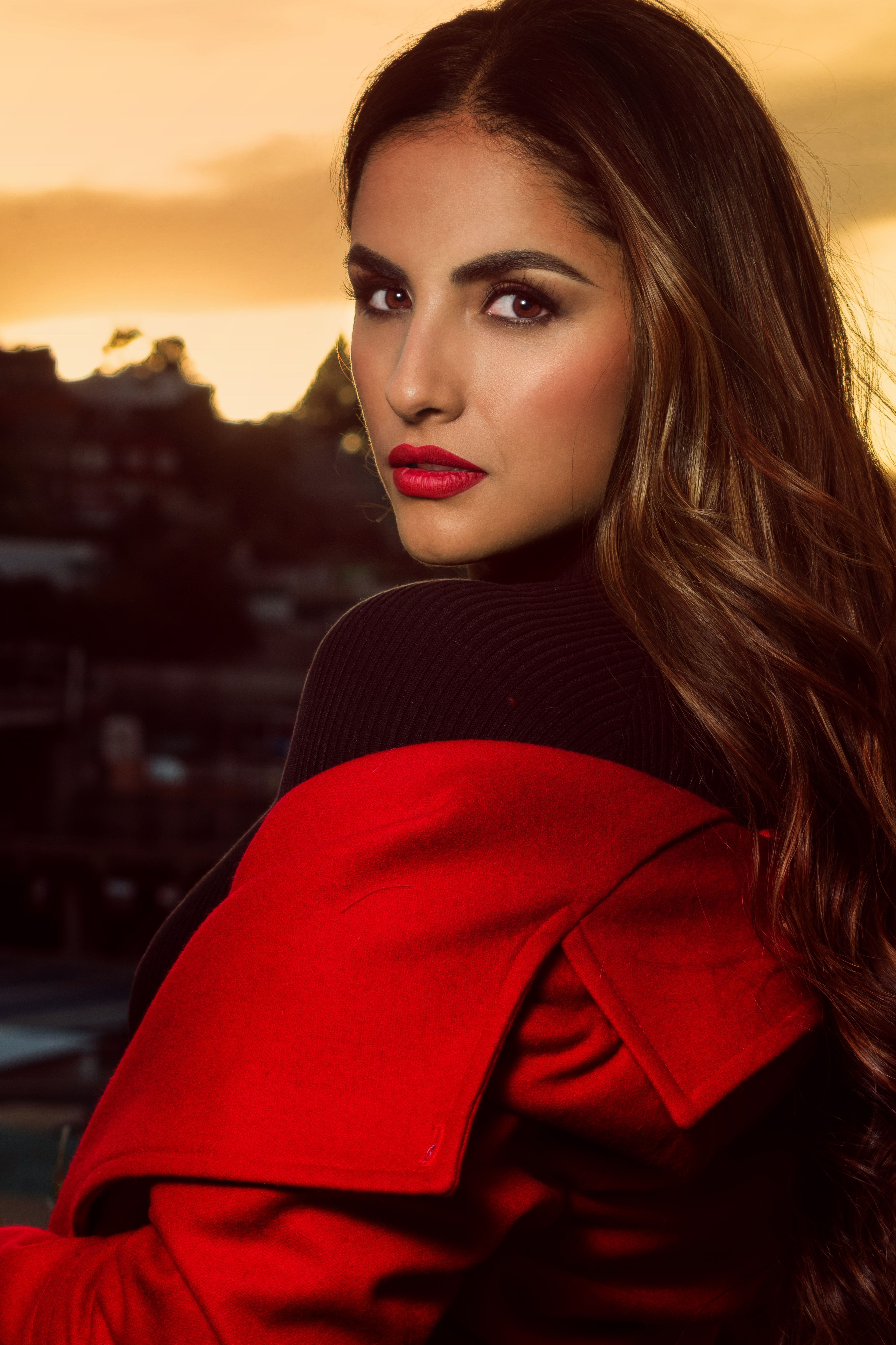Elegant woman with red lipstick in a red coat at sunset in Tlaxcala, Mexico. Vibrant and dramatic.