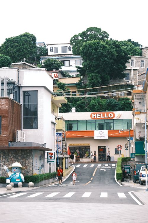 Free Charming urban street scene with a 'Hello' sign, lush greenery, and modern architecture. Stock Photo