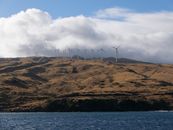 Scenic view of wind turbines on a hillside in Maui, Hawaii, under cloudy skies.