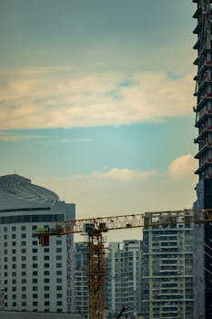 City skyline with construction cranes against a sunset sky, showcasing urban growth.