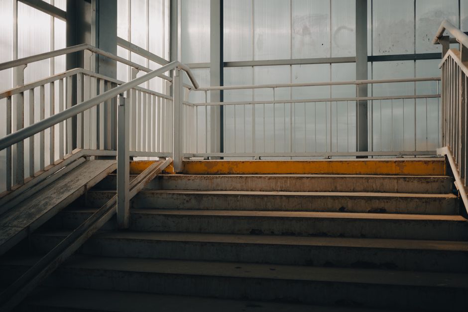 Empty industrial-style staircase indoors with metal railings and natural lighting.