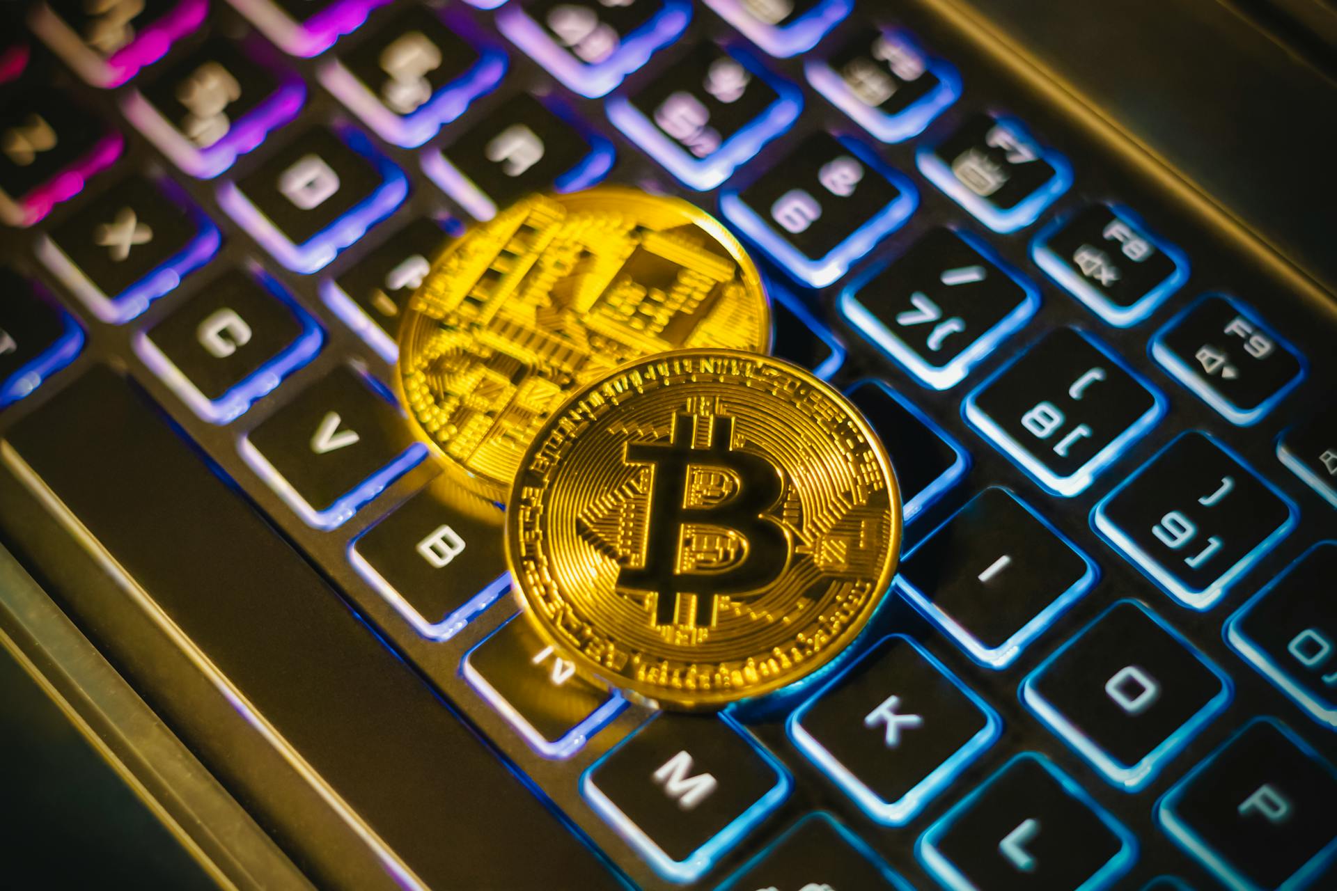 Gold bitcoins on a colorful illuminated keyboard, symbolizing cryptocurrency and technology integration.