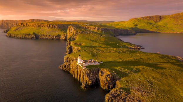 Breathtaking aerial shot of Neist Point Lighthouse during a golden sunset on the Isle of Skye, Scotland.