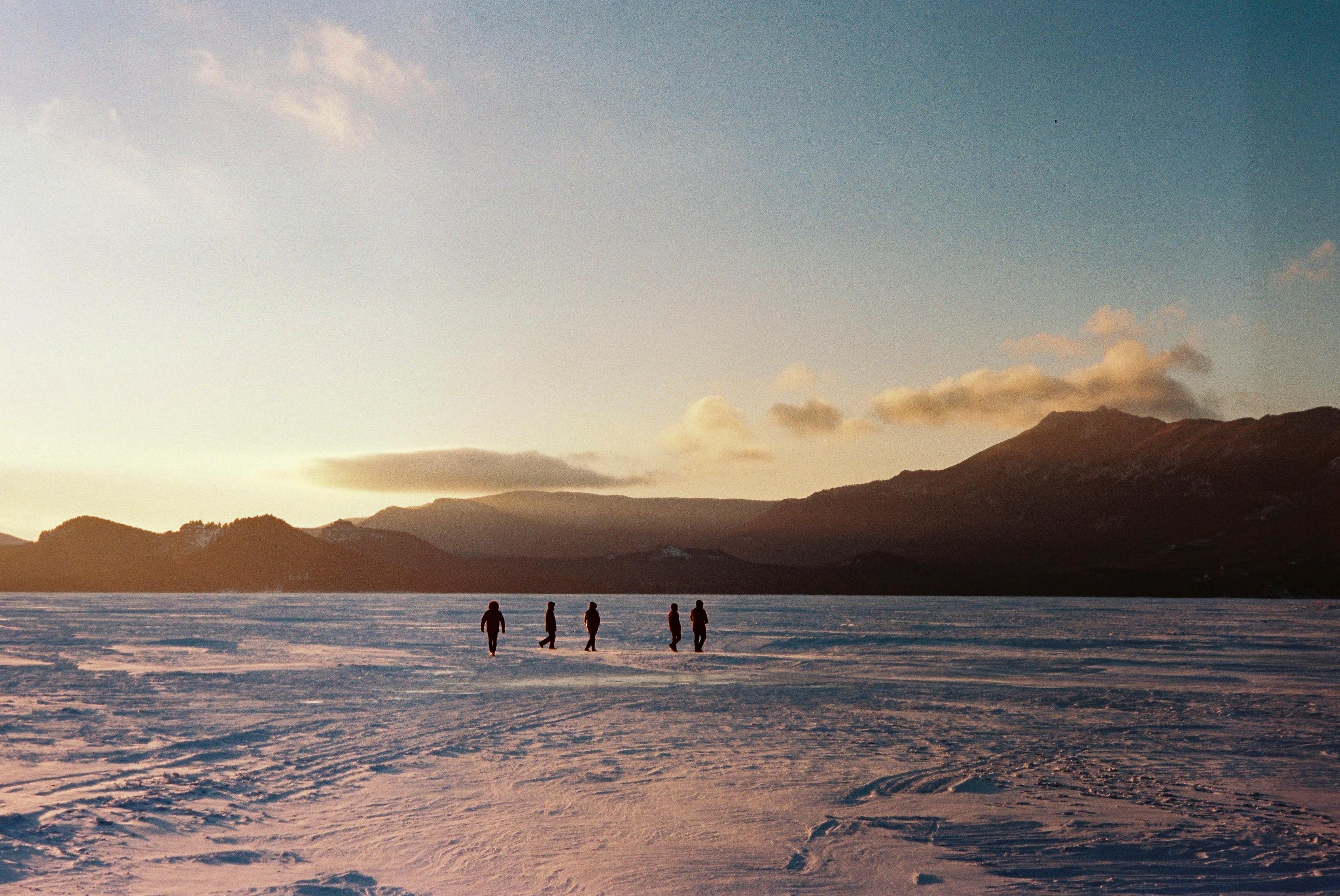 Five people walking across a frozen lake during sunset in Kazakhstan's Akmola region.