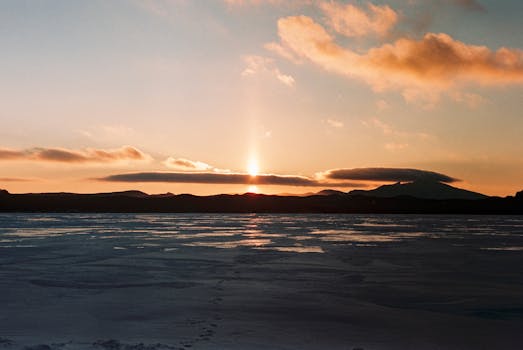 Stunning sunset view over a frozen lake with distant mountains in Акмолинская область, Kazakhstan.