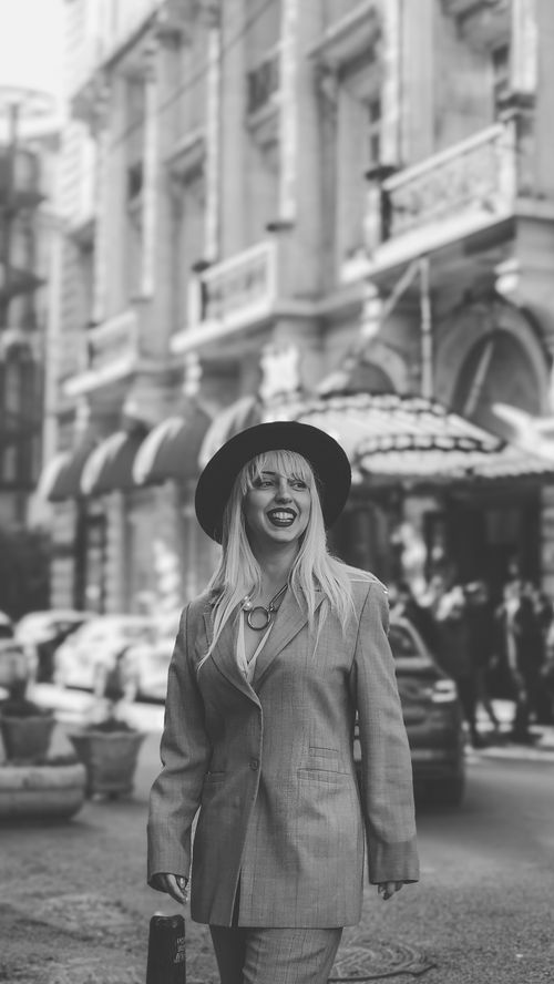 Free Elegant woman in a suit and hat walks in a historic urban street in black and white. Stock Photo